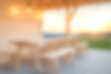 Ahşap mobilyalar, yumuşak ışıklandırma ve güzel bir gün batımı arkaplanı olan sakin bir açık hava yemek alanı rahatlama ve keyif için mükemmel bir ortam yaratır..