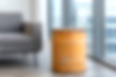 Canlı turuncu bir yan masasının yanında şık gri koltuğu olan rahat, modern bir yaşam alanı, doğal ışıkla dolu sıcak ve davetkar bir atmosfer yaratıyor..