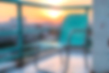 Havuz kenarındaki şık bir sandalyenin üzerinde sakin ve bulanık bir günbatımı manzarası, modern bir açık alanda sıcak renkler sergiliyor, rahatlamak ve kaçmak için ideal..