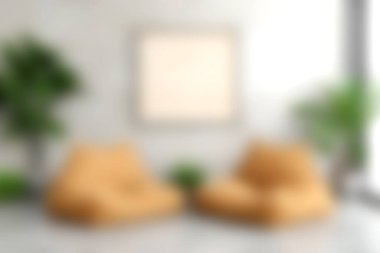 Yeşil bitkilerle tamamlanmış sarı fasülye koltukları olan rahat bir oturma odası. Bu minimalist alan rahatlamak için mükemmel, sıcak ve davetkar bir atmosfer sunuyor..