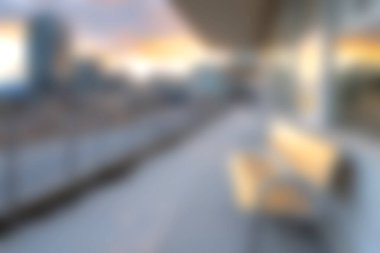 Yumuşak odaklı görüntü, şehir silueti üzerinde sakin bir günbatımı olan modern bir balkon sergiliyor, rahatlama ve kentsel yaşam tarzını çağrıştırmak için mükemmel..