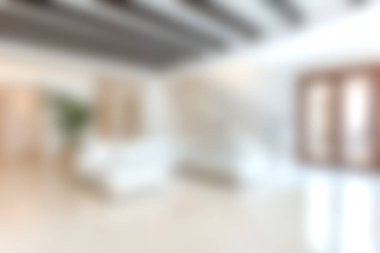 Büyük pencereleri ve minimalist dekorları olan parlak, modern bir oturma odası. Mekan konfor ve zarafeti ahşap kirişler ve açık renklerle birleştiriyor..