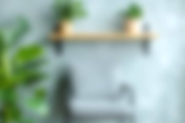 Kapalı mekandaki minimalist bir sahne, yumuşak ve bulanık bir arka plana karşı saksı bitkileriyle süslenmiş şık bir raf sergiliyor ve sakin bir ortam yaratıyor..