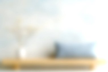 Bu yumuşak odaklı görüntü, içinde bir yastık ve çiçek düzeninin bulunduğu rahat bir ev görüntüsünü ahşap bir rafta, huzurlu bir atmosfer yaratıyor..