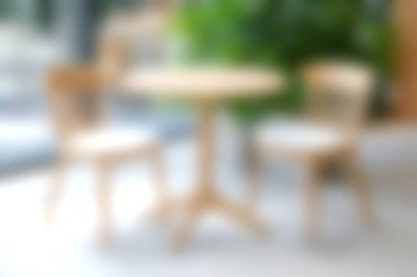 İki sandalyeyle eşleştirilmiş şık bir ahşap masa, parlak ışık ve canlı yeşillikle güçlendirilmiş, rahat ve davetkar bir iç mekan ortamı yaratır..