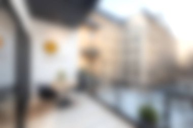 Modern mobilyaların, bitkilerin ve gün batımında şehir binalarının manzarasının olduğu rahat bir balkon. Rahatlama ve ev ortamı için ideal..