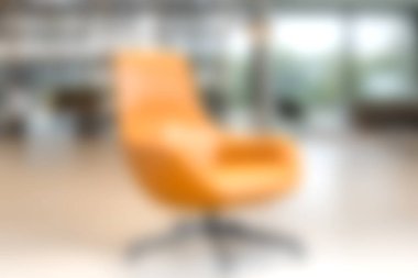 Modern ofis ortamında modern bir turuncu sandalye, geniş doğal ışık, çağdaş tasarım ve davetkar konfor. Çalışma alanları için ideal.