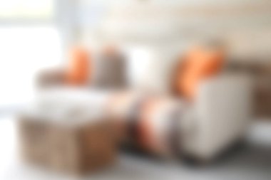 Turuncu yastıklı rahat bir sandalyeye sahip şık bir oturma odası, doğal ışıkla aydınlanıyor, dinlenmek için sıcak ve davetkar bir atmosfer yaratıyor..