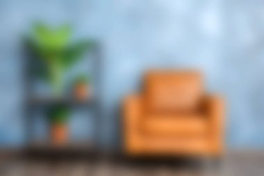 Bu resim, kahverengi koltuğu ve canlı yeşil bitkisi olan rahat bir oturma odası ortamını gösteriyor. Arka planda, iç dekorasyon için ideal yumuşacık mavi bir duvar var..