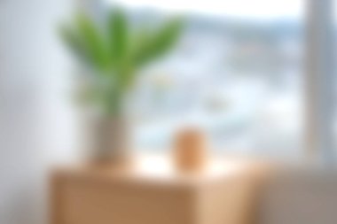 Saksı bitkisi ve ahşap dekor üzerine yumuşak bir odak içeren sakin bir iç mekan, modern bir ev ortamında huzurlu ve rahat bir atmosfer yaratıyor..