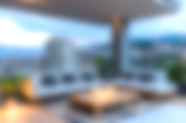 Bu resim modern mobilyalarla dolu rahat bir açık hava salonu gösteriyor, alacakaranlıkta sakin bir şehir manzarası sunuyor. Rahatlamak ve rahatlamak için mükemmel..