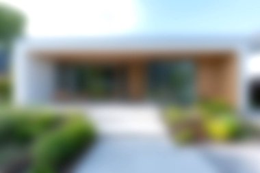 Modern bir eve girişte, parlak gün ışığında sakin ve davetkar bir atmosfer yaratan, verimli yeşil bir yol çevreleyen parlak bir tasarım sergilenir..