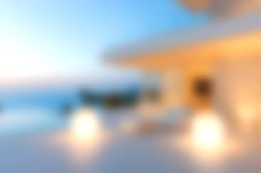 Günbatımında sakin bir okyanus zeminine karşı aydınlatılmış, modern bir dinlenme odası olan sakin bir açık alan. Rahatlamak için mükemmel..