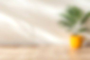 Ahşap bir yüzeye yerleştirilmiş parlak sarı bir tencerede saksı bitkisinin yumuşak odak noktası doğal ışık ile rahatlatıcı ve şık bir iç atmosfer yaratıyor..