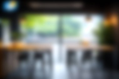 Doğal ışık getiren ve dışarıdaki yemyeşil alanları gösteren geniş pencereli rahat, modern bir kafe. Minimum dekor rahatlama için davetkar atmosferi artırır..