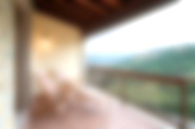 Bir balkonda rahat ahşap sandalyeler bulunan sakin bir ortam. Dağlık manzarası nefes kesici. Yumuşak doğal ışık sükuneti arttırır..