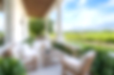 Rahatlamak ve rahatlamak için ideal yeşil tarlaları ve mavi gökyüzünü gören rahat mobilyaların bulunduğu sakin bir verandanın tadını çıkarın..