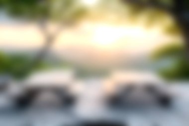 Gün batımının hafif ışığı park halindeki arabaları aydınlatıyor ve doğa ile çevrili sakin bir açık hava ortamı yaratıyor. Güzel manzara hafifçe bulanık, davetkar sükunet.