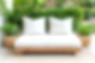 Bu resim, ferahlatıcı bir atmosfer için yemyeşil yemyeşil ile çevrili, beyaz yastıklı rahat minimalist bir kanepeyi sergiliyor..