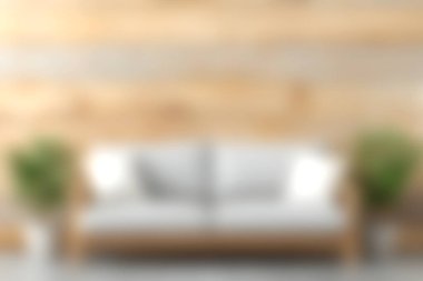 Kırsal bir ahşap duvara dayanan minimalist beyaz bir kanepenin canlı yeşil bitkilerle eşleştirildiği güzel bir oturma odası sahnesi. Tasarım ilhamı için ideal.