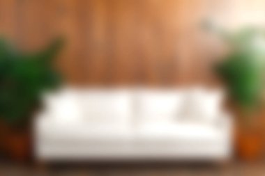 Bu resimde doğal ahşap bir duvara karşı şık beyaz bir kanepe sergileniyor, yemyeşil bitkilerle tamamlanmış, modern iç mekanlar için rahat ve zarif bir ortam yaratıyor..