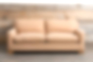 Yumuşak bej bir kanepe, rahat yastıklarla bezenmiş modern bir oturma odasında, doğal ışıkla aydınlatılmış, zarif tasarım ve konforla aydınlatılmış..