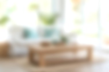 Parlak ve davetkar bir oturma odası, içinde doğal ışıkla aydınlatılmış ahşap bir sehpa ve rahat tekstil var. Rahatlama ve toplanma için ideal..