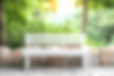 Bereketli yeşillik ve yumuşak güneş ışığıyla çevrili beyaz ahşap bir bankın yer aldığı huzurlu bir bahçe sahnesi. Huzur ve rahatlama uyandırmak için ideal..