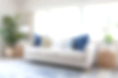 Dekoratif yastıklarla süslenmiş, parlak doğal ışıkla aydınlatılmış, davetkar atmosferi artıran şık beyaz bir kanepenin olduğu rahat bir oturma odası..