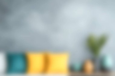 Renkli yastıkların olduğu rahat bir oturma odası sahnesi, çağdaş bir dekor tarzı, ve gri bir duvar arkaplanı. İç tasarım fikirlerini sergilemek için mükemmel..