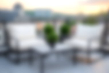 Rahat sandalyeler ve canlı yeşil bitkilerin şehir çatısı ortamında güzel bir gün batımına karşı durduğu sakin bir açık hava oturma düzeneği..