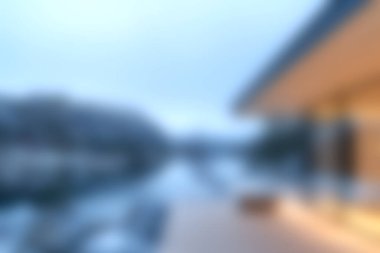 Günbatımında göl kenarındaki modern mimarinin büyüleyici bir görüntüsü, dingin ve rahatlatıcı bir atmosfer yaratan yumuşak mavi bir palet içerir..