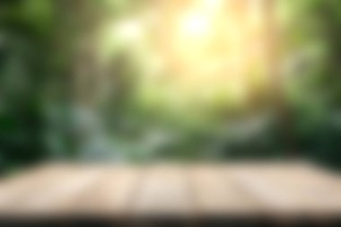 Huzurlu ve rüya gibi ahşap bir masa canlı yeşillik ve huzur veren güneş ışığıyla dolu bulanık bir orman arka planına karşı, huzur ve sükuneti çağrıştırıyor..