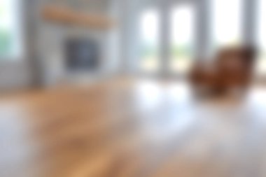 Ahşap zemin ve geniş pencereli, doğal ışığın boşluğu doldurarak sıcak ve davetkar bir atmosfer yaratmasına olanak sağlayan rahat bir oturma odası..