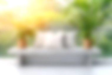 Parlak ve cezbedici bir modern oturma odası şık beyaz bir kanepe dekoratif yastıklar ve yumuşak doğal ışık altında yemyeşil bitkiler, sakin bir atmosfer yaratıyor..