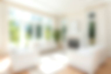 Bu görüntü, geniş pencerelerden süzülen parlak doğal ışıkla huzurlu bir oturma odası yakalıyor, sıcak ve rahat bir atmosfer yaratıyor, rahatlık ve sükunet için ideal..