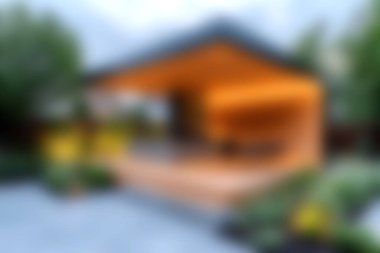 Canlı yeşilliklerle çevrili ahşap mimari içeren çarpıcı bir modern bahçe terası. Doğal ışık altında rahatlama ve açık hava buluşmaları için mükemmel..