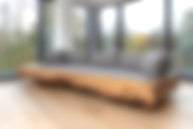 Pofuduk gri yastıklı modern bir ahşap kanepe, güneş ışığıyla aydınlatılmış bir odayı aydınlatarak, çarpıcı doğa manzaralı sakin bir ortam sunuyor. Rahat bir rahatlama için ideal..