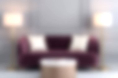 Bu resim modern bir lambayla tamamlanmış, çağdaş bir oturma odasında davetkar ve zarif bir ortam yaratan, beyaz yastıklı şık bir mor kanepe sergiliyor..