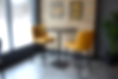 İçinde iki sarı sandalye ve modern bir masa olan rahat bir köşe, sosyal toplantılar için mükemmel. Bu parlak minimalist iç mekan hoş bir atmosfer yaratıyor..