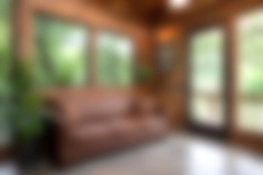 Etrafı yemyeşil bitkilerle çevrili kahverengi deri bir kanepenin olduğu rahat bir oturma odası. Doğal ışık boşluğu doldurur, sıcak ve davetkar bir atmosfer yaratır..