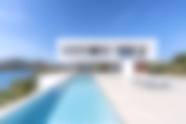 Bu resim, temiz havuzlu, nefes kesici bir deniz manzarası ve gökyüzü sunan çarpıcı, modern bir villayı gösteriyor..