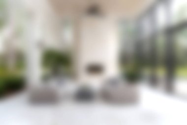 Bu resim, geniş pencereli, şık mobilyalı ve yeşil bitkilerli modern bir oturma odasını sergiliyor. Rahatlamak için mükemmel ve rahat bir ortam yaratıyor..