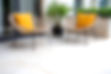 Bu resim, şık sandalyeler ve yemyeşil bitkiler üzerinde sarı yastıkların yer aldığı rahat ve modern bir avlu sergiliyor, davetkar ve sakin bir atmosfer yaratıyor..