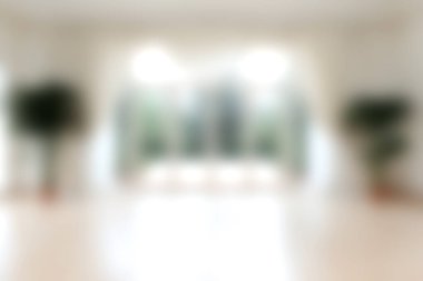 Geniş pencereler ve kapalı bitkiler içeren, aydınlık ve ferah bir iç mekanın bulanık görüntüsü, dinginlik için mükemmel ve davetkar bir atmosfer yaratıyor..