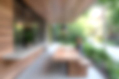 Bu resim, bereketli yeşil bir bahçeye karşı ahşap mobilyaların sergilendiği rahat bir açık hava oturma düzenini yakalar, rahatlamak için davetkar ve huzurlu bir alan yaratır..