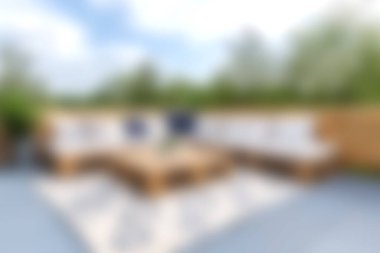 Bu resim, yemyeşil yemyeşil ve rahatlamak için mükemmel mavi gökyüzü ile çevrili rahat bir oturma düzenine sahip rahat bir bahçe düzenine sahiptir..