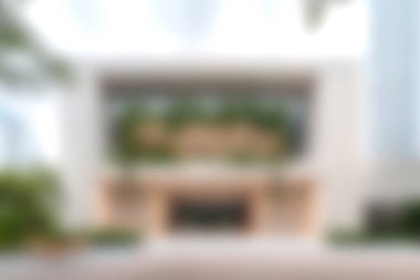 Bu resim, yeşil bitkilerle çevrili geniş pencereli modern bir binanın zarif cephelerini yakalıyor ve uyumlu bir atmosfer yaratıyor..