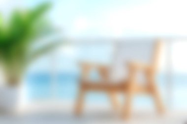 Konforlu ahşap bir sandalye, sakin bir okyanus manzarasına bakan bir balkonda, yumuşak odaklı canlı yeşil bir bitki eşliğinde, barışçıl bir atmosfer yaratıyor..