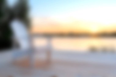 Suyun kenarında beyaz bir sandalyenin olduğu huzurlu bir günbatımı manzarası huzur ve huzuru çağrıştırıyor. Rahatlamak ve doğanın güzelliğini yakalamak için mükemmel..